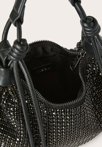 Bolso negro con adornos de strass, detalles de cuero suave y cierre con cremallera. El interior está forrado y es espacioso.