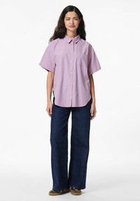 Korte mouwen overhemd met knopen in roze en witte strepen, met een borstzak en zijsplitten, gecombineerd met brede donkerdenim broek.