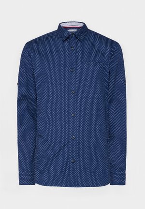 Navy blue shirt with white polka dots, long sleeves, button-up front, single chest pocket, and contrasting inner collar detail.