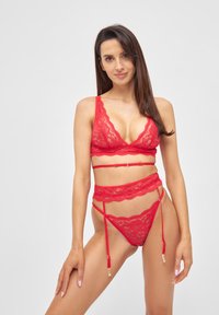 Rotes Spitzen-BH-Set mit einem Bralette mit gewelltem Rand und passendem hochgeschnittenem Strapsgürtel, akzentuiert mit goldfarbenen Beschlägen.