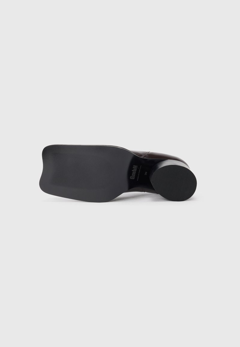 Chaussure en cuir noir avec un bout arrondi, tige lisse, semelle en caoutchouc et motif de grip texturé. Dispose d'un talon bloc solide pour la stabilité.