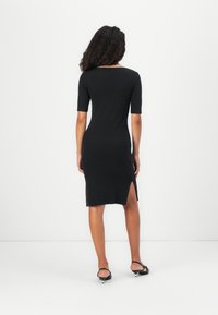 Form-fitting black dress with a scoop neckline and short sleeves. Features a side slit and textured fabric for added visual interest.