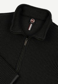 Melns ribots pulovers ar rāvējslēdzēju, augstu apkakli un Colmar Originals etiķeti ar sarkaniem, baltajiem un ziliem akcentiem.