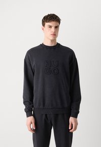 Czarny sweatshirt z prążkowanym okrągłym dekoltem, z haftowanym logo "HUGO" na środku, wykończony elastycznymi mankietami i teksturowanym dołem.
