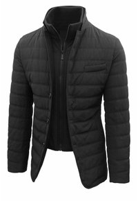 Giacca nera trapuntata con colletto alto, chiusura con zip e texture a costine. Presenta diversi taschini e una vestibilità aderente.
