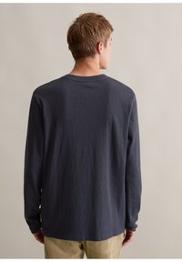 Marineblaues Langarm-T-Shirt mit Rundhalsausschnitt und gerippten Bündchen, aus weichem Baumwollstoff gefertigt. Die Rückseite hat eine glatte Textur und ein schlichtes Design.