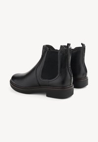 Botine Chelsea din piele neagră cu panouri elastice pe lateral, vârf rotund și toc jos. Textură netedă cu detalii de cusătură contrastante.