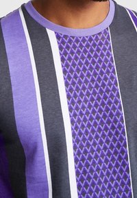 Short-sleeve t-shirt with purple and gray stripes, featuring a diamond pattern on the front and a contrasting round neckline.