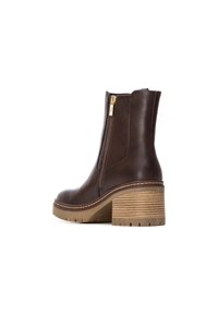 Botín de cuero marrón con cremallera lateral, tacón texturizado y plataforma de madera acanalada. Presenta una silueta elegante y una construcción robusta.