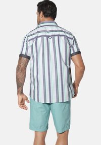 Kurzarm, gestreiftes Hemd in Grün, Lila und Weiß, mit einem umlegbaren Kragen und dunklen blauen Akzenten; kombiniert mit hellblauen Shorts.