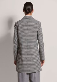 Blazer met pied-de-poule patroon, een getailleerde pasvorm, gedetailleerde stiksels, sjawlrevers en lange mouwen in zwart en wit.