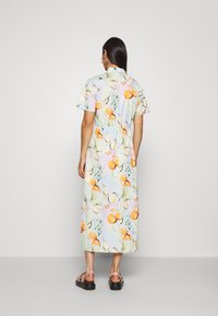 Lekka, pastelowa sukienka maxi w owocowy wzór. Krótkie rękawy, kołnierzyk zapinany na guziki, wcięcie w talii i długość do kostek. Noszona w połączeniu z sandałami.