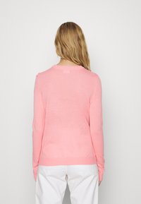 Rosa gestrickter Pullover mit langen Ärmeln und rundem Halsausschnitt. Das Material ist leicht und leicht strukturiert und hat einen gerippten Saum.