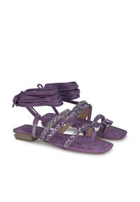 Sandalias de ante moradas con múltiples tiras finas, adornadas con strass y un pequeño tacón cuadrado. Cuentan con una suela plana y un diseño de punta abierta.