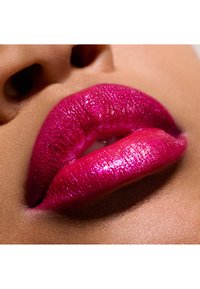 Odważne, lśniące fuksjowe usta z błyszczącym wykończeniem. Gładka textura z wyraźnymi krawędziami, umieszczona na ciepłym, neutralnym tle.