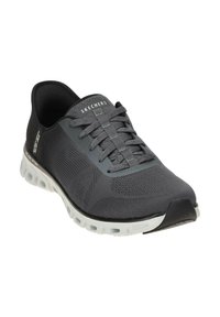 Scarpa sportiva Skechers di colore grigio scuro con tomaia in rete e accenti grigi. Presenta una suola bianca imbottita con tacco arrotondato per il massimo comfort.
