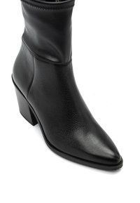 Botín de cuero negro hasta el tobillo con punta afilada y acabado texturizado. Presenta un tacón cuadrado y costuras sutiles a lo largo del borde superior.