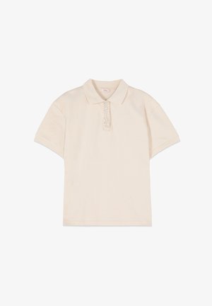 Polo beige de manga corta con cuello y una sola tapeta con pequeños botones decorativos que parecen perlas.