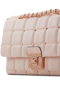 Růžová prošívaná kabelka z umělé kůže, s pozlacenými prvky a pyramidovými hroty, s řetězovým popruhem a kovovým zapínáním.
