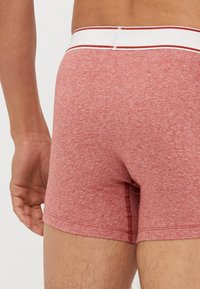 Boxershorts od mješavine pamuka u heather crvenoj boji s bijelim pojasom koji ima crvenu prugu. Mekana tekstura i prilagođen dizajn.