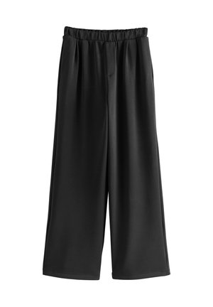 Voľné čierne nohavice so širokými nohavicami, elastickým pásom a prednými záhybmi, vyrobené z hladkej látky, zobrazené na bielom pozadí.