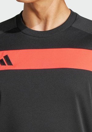 Zwart atletisch shirt met een geribbelde rode horizontale streep over de borst, met een zwart logo in de linkerbovenhoek.