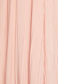 Vaaleanpunainen poimutettu kangas, jossa on pystysuoria viivoja, esittelee tekstuuri- ja sileäpintaisuutta. Tasaisesti sijoittuneet, pehmeät taitteet luovat syvyyttä.