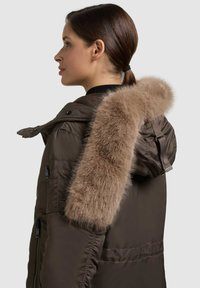 Brun parkajacka med foder av päls i huvan, har dragkedja, sidofickor och ett vattenavvisande material. Utsmyckad med en avtagbar pälsdetalj.