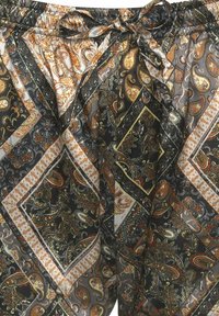Trykte bukser med et sort, guld og orange paisley-mønster, fremstillet af et struktureret stof, med elastisk talje og sløjfe detalje.