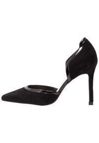 Chaussure à talon haut en daim noir avec un bout pointu, des accents brillants et un design avec découpe sur le côté. Hauteur du talon : environ 10 centimètres.