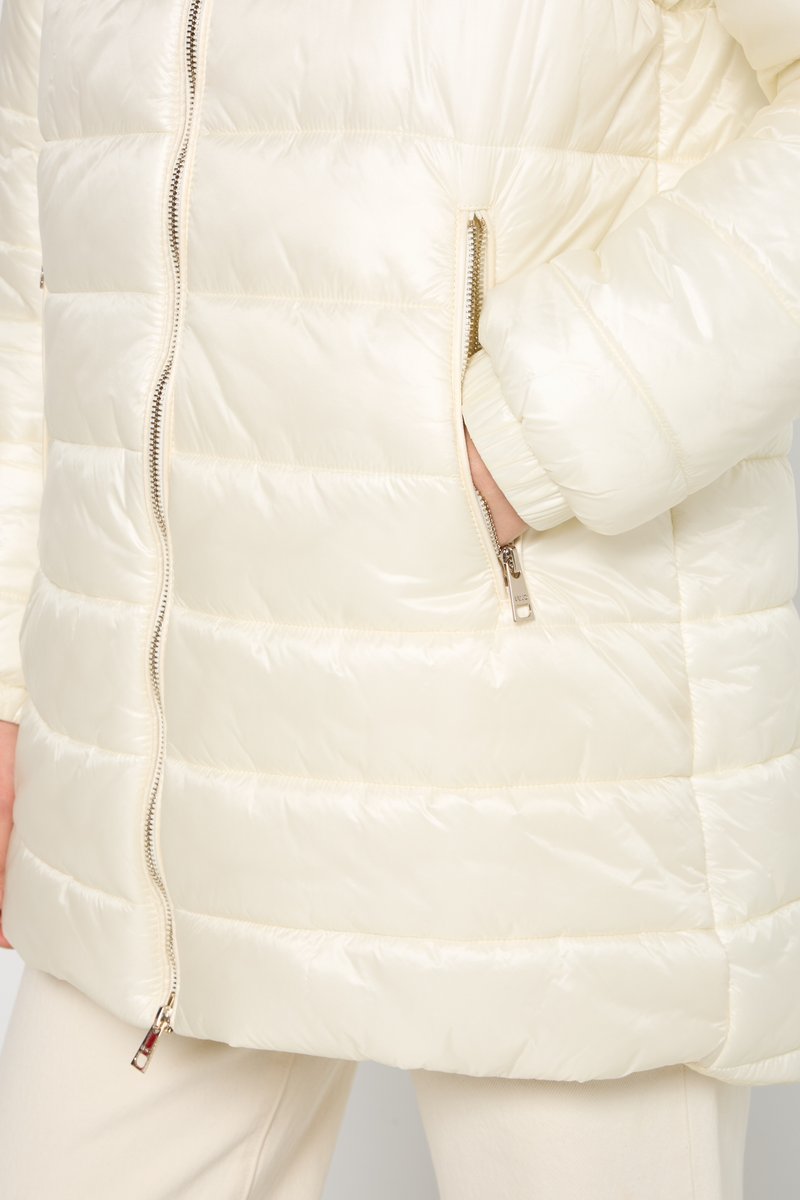 Giubbotto imbottito di un leggero color crema, caratterizzato da un design a righe orizzontali, con due tasche con zip e polsini elastici per una vestibilità sicura. Texture liscia e brillante.