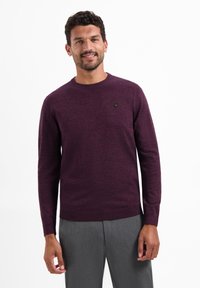 Bordeauxkleurige trui met een ronde hals en lange mouwen, met een klein embleem op de borst. Zachte textuur en normale pasvorm.