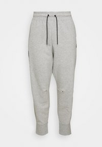 Calças de moletão cinzentas com cintura ajustável por cordão, pernas afuniladas e punhos com canelado; apresenta bolsos laterais e detalhes minimalistas em preto.