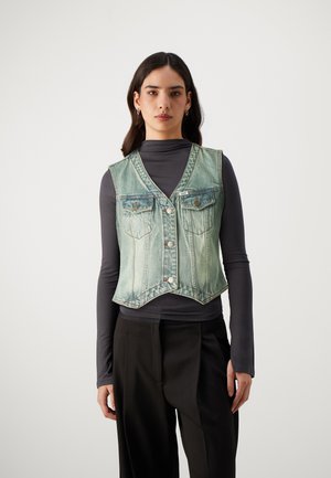 Denimvest i lys blå med et slittet utseende; har V-hals, fire lommer og sølvknapper. Kombinert med en mørk topp og bukser.