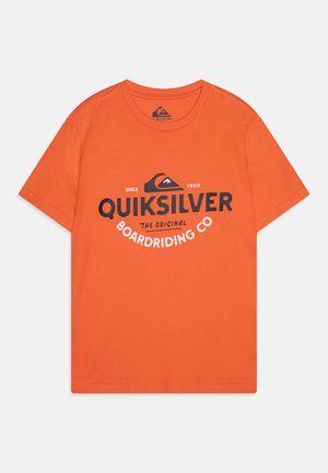 T-shirt en coton orange avec un grand logo Quiksilver noir et blanc et un motif de montagne. Manches courtes et design col rond.
