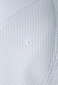 White mesh fabric, textured with a grid pattern, features a central circular button and smooth, seamless edges for a refined look.
