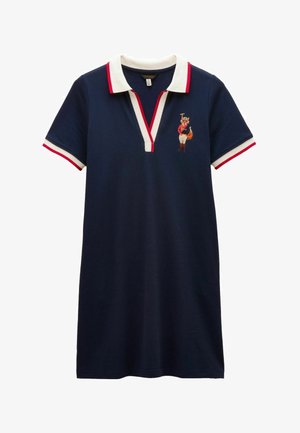 Robe polo bleu marine avec col blanc et bordure rouge, ornée d'un renard brodé en veste rouge tenant un club de golf sur la poitrine.