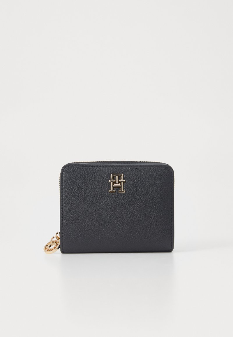 Black leather wallet with a textured finish, featuring a gold logo on the front and a zip closure, including a decorative gold charm.