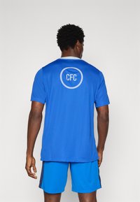 Blue athletic shirt with short sleeves and a circular "CFC" logo on the back, paired with blue shorts. Smooth, lightweight fabric.