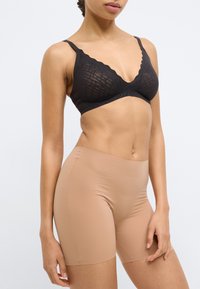 Μαύρο δαντελένιο σουτιέν bralette με κυματι στά άκρα και ρυθμιζόμενους ιμάντες, συνδυασμένο με μπεζ αθλητικά σορτς χωρίς ραφές από απαλό, ελαστικό ύφασμα.