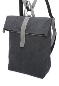 Zaino in canvas grigio con patta pieghevole, tracolla grigia testurizzata e un logo discreto sul fronte. Presenta spallacci regolabili per il massimo comfort.