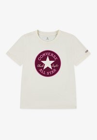 Kremfarget bomull t-skjorte med et sirkulært burgunderlogo med en hvit stjerne og teksten "Converse" og "Chuck Taylor". Korte ermer.