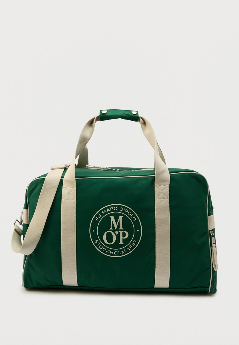 Πράσινη τσάντα duffel με μπεζ ιμάντες, κλείσιμο με φερμουάρ και στρογγυλό λογότυπο με την επιγραφή "Marc O'Polo Stockholm 1967" στο μπροστινό μέρος.