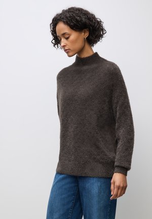 Maglione marrone scuro morbido con un collo alto e una vestibilità rilassata. Presenta maniche lunghe e una superficie tessurizzata, abbinato a jeans blu.