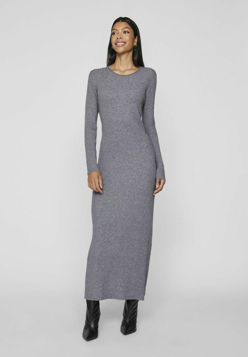 Gray ribbed knit maxi dress with long sleeves and a crew neckline, paired with sleek black heeled boots. Smooth texture, fitted silhouette.