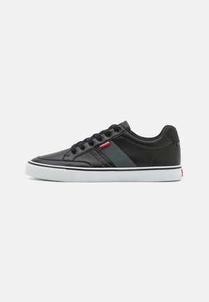 Czarny niskoprofilowy sneaker z białą podeszwą, czarnymi sznurowadłami i małą czerwoną metką z logo Levi's z boku.