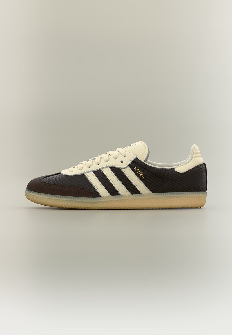 Black and cream Adidas Samba sneaker with gum sole, cream laces, and three cream stripes on the side, shown in profile on a neutral background.
