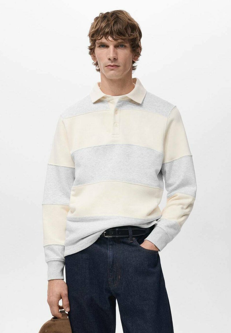 Polo à manches longues rayé gris clair et crème avec une patte de boutonnage, associée à un jean en denim foncé et une ceinture marron.