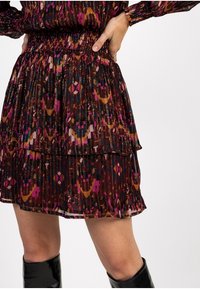 Falda plisada multicolor con cintura fruncida, con un diseño en capas en tonos de burdeos, rosa y marrón.