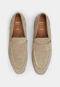 Beige Wildleder Slipper mit gestickter Zehenpartie, Lederfutter und goldgeprägtem Branding. Glatte Textur, leichtes Design und Schlupfstil.